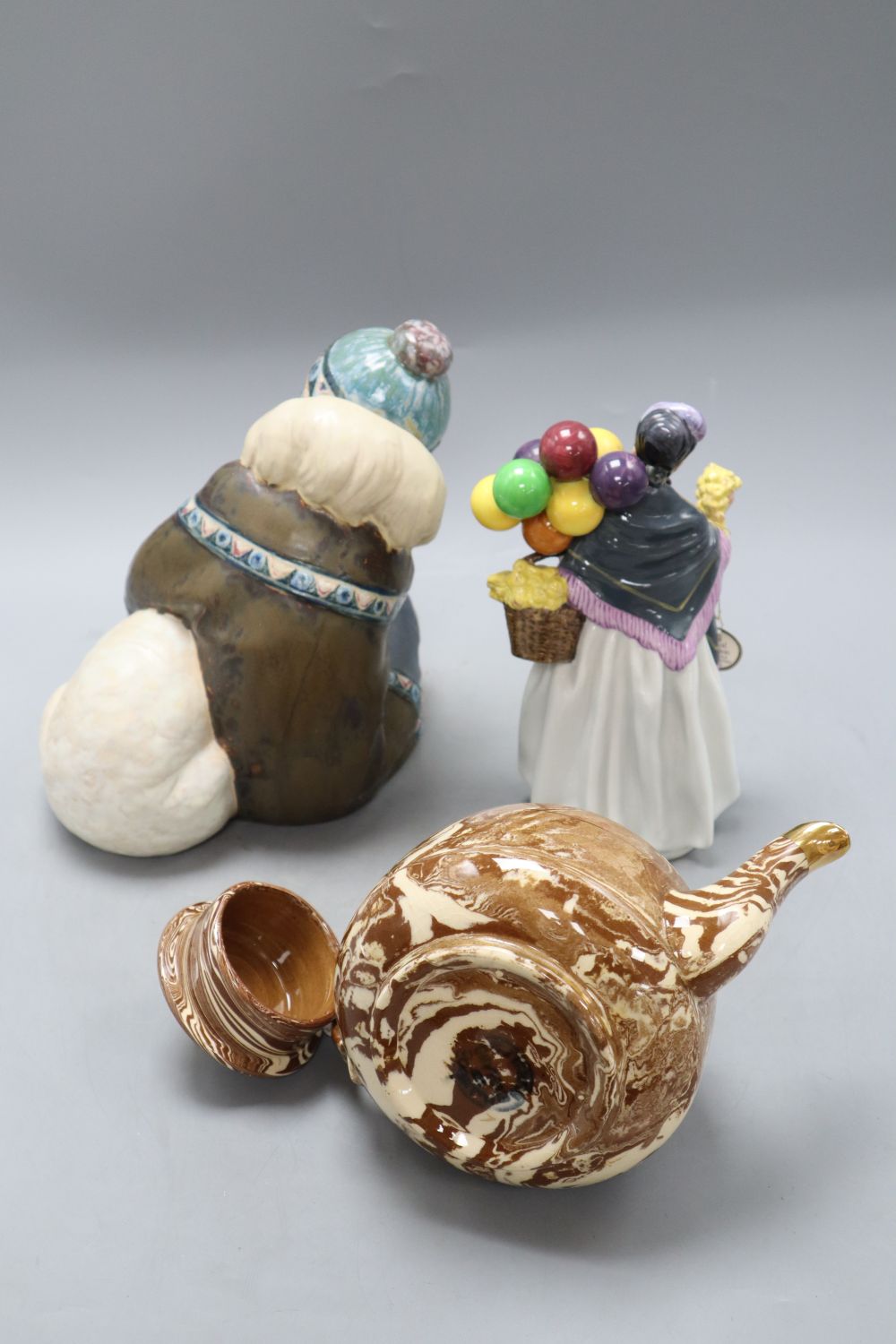 A Lladro stoneware group, a Doulton figure Biddy Penny Farthing HN1843 and a marbleware teapot